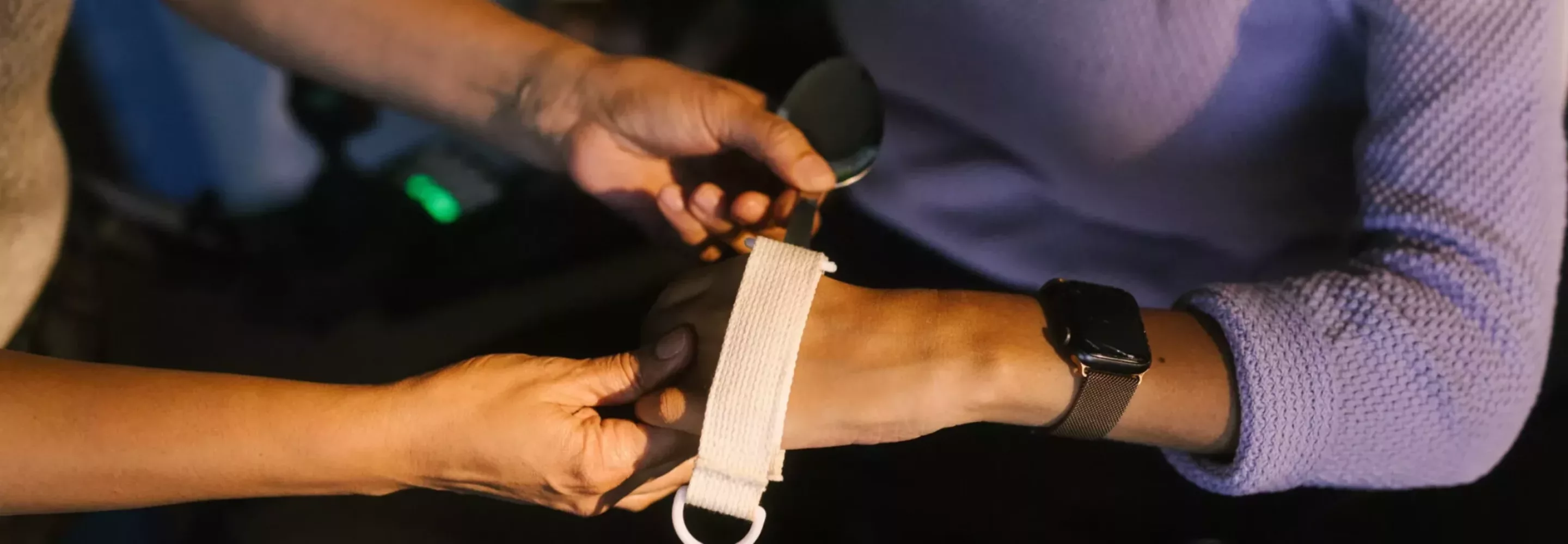 Zorgmedewerker helpt iemand met een polsband tijdens werken in de zorg in Arnhem.